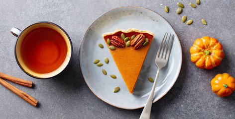 Wall Mural - Pumpkin pie on a plate with cup of tea. Grey background. Top view.