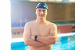 © amixstudio - Close up portrait of sporty muscular man in swimming goggles and cap with a naked torso on background of swimming pool indoors