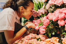 Side View Of A Young Woman Smelling The Flowers With Closed Eyes