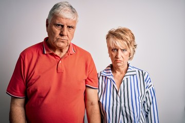 Wall Mural - Senior beautiful couple standing together over isolated white background depressed and worry for distress, crying angry and afraid. Sad expression.