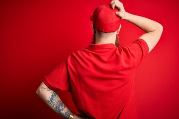 Canvas Print - Young handsome delivery man wearing glasses and red cap over isolated background Backwards thinking about doubt with hand on head