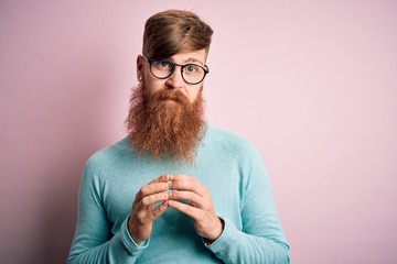 Poster - Handsome Irish redhead man with beard wearing glasses over pink isolated background Hands together and fingers crossed smiling relaxed and cheerful. Success and optimistic