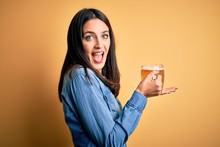 Young Woman With Blue Eyes Drinking Jar Of Beer Standing Over Isolated Yellow Background Pointing Aside With Hands Open Palms Showing Copy Space, Presenting Advertisement Smiling Excited Happy