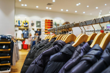 Wall Mural - Modern fashion store. Buyers choose clothes. Shirts, hoodies, blouses and half-sweaters, a sweater on a hanger in a clothing store close-up. Sale and shopping in stores. Soft focus.