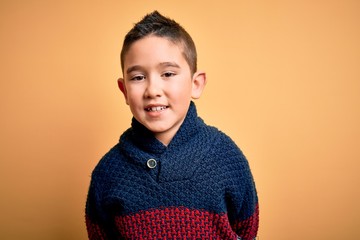 Sticker - Young little boy kid wearing winter sweater over yellow isolated background with a happy and cool smile on face. Lucky person.