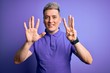 © Krakenimages.com - Young handsome modern man wearing casual purple t-shirt over isolated background showing and pointing up with fingers number eight while smiling confident and happy.