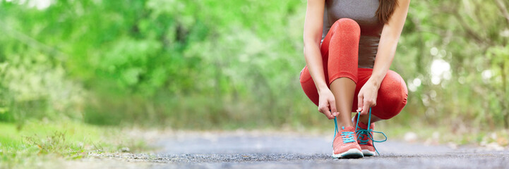 Exercise and sport running shoes runner woman tying laces getting ready for summer run in forest park panoramic banner header crop. Jogging girl exercise motivation heatlhy fit living.