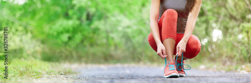 Fotomural Exercise and sport running shoes runner woman tying laces getting ready for summer run in forest park panoramic banner header crop