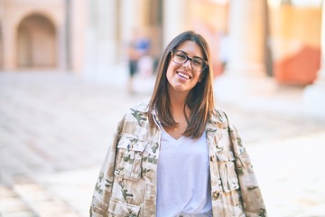 Young beautiful woman smiling happy and confident. Standing with smile on face at the town street