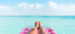 Beach summer vacation woman relaxing on pool float taking feet selfie pov of legs sunbathing relax on pink air mattress inflatable toy floating on blue ocean background panoramic banner.