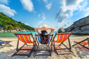 Wall Mural - Woman with hat sitting on chairs beach in beautiful tropical beach. Woman relaxing on a tropical beach at Koh Nangyuan island.