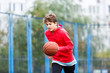 © Natali - Cute boy in red t shirt plays basketball on city playground. Active teen enjoying outdoor game with orange ball. Hobby, active lifestyle, sport for kids.