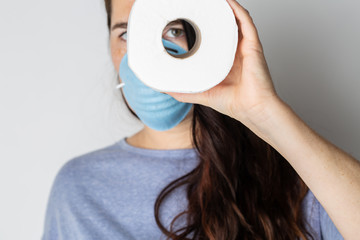 A woman is wearing a face mask for protection from the Corona Virus and has stocked up on her toilet paper stash in case of quarantine.