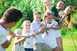 © JackF - Happy  children with parents playing active games in summer park, tugging war