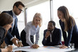 © fizkes - Concentrated multiracial colleagues brainstorm discussing business company ideas at briefing in office, focused diverse businesspeople cooperate work together with paperwork at boardroom meeting