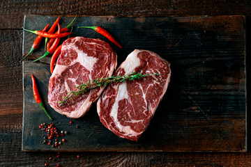 Wall Mural - Two classic fresh rib eye steaks on a wooden Board, top view