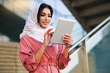 © javiindy - Young Arab woman wearing hijab using digital tablet outdoors