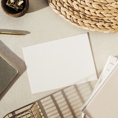 Wall Mural - Flatlay blank paper sheet, notebooks, clips in wooden bowl, straw stand on beige concrete background. Home office desk workspace. Business, work template. Flat lay, top view.