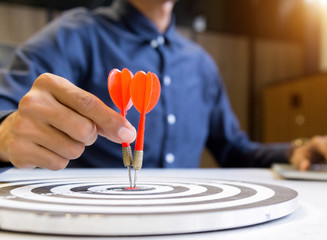 Businessman holding a darts aiming at the target center,business growth success concept.