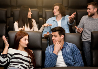 Wall Mural - Young friends talking while waiting for film to start in cinema