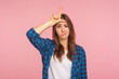 Portrait of depressed unlucky girl in checkered shirt showing loser gesture with fingers on forehead, upset about failure, dismissal at work, blaming herself for mistake. indoor studio shot, isolated