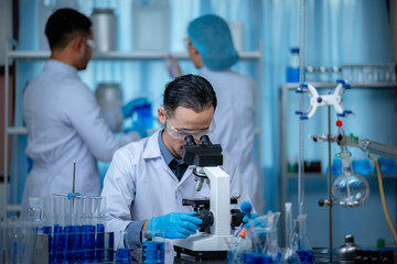 Young scientist looking through a microscope in a laboratory. Young scientist doing some research.