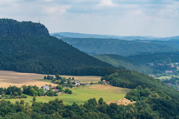 Königstein fortress on the banks of the Elbe river, green landscape with mountains in the background. Dresden, Saxon Switzerland, Germany.