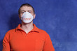 © Sergei - Male European in a medical mask. The inscription on the mask 'STOP'. Red shirt, casual wear, blue background. Viral diseases, coronovirus.