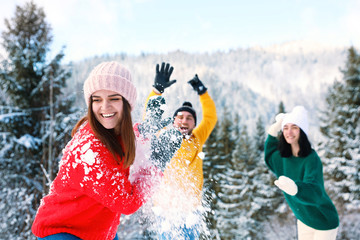 Wall Mural - Happy friends playing snowballs outdoors. Winter vacation