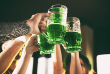 Group Of Friends Toasting With Green Beer In Pub, Closeup. St. Patrick's Day Celebration