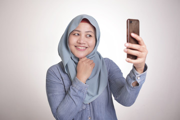 Wall Mural - Muslim Woman Smiling and Taking Selfie Picture of Her Self on Phone