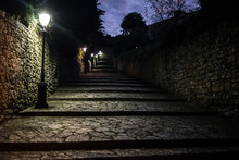 Dark Medieval Cobbled Alley At Night With Several Street Lamps Providing Light