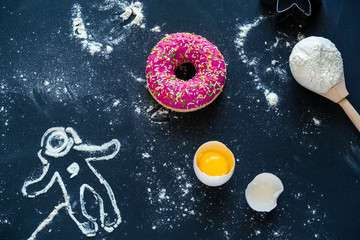 Wall Mural - top view flat lay pink a donut , a broken egg, a spoon with flour and a silhouette of an astronaut made of flour, a postcard for the day of cosmonautics