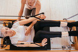 Woman practicing stretching exercise on reformer in gym