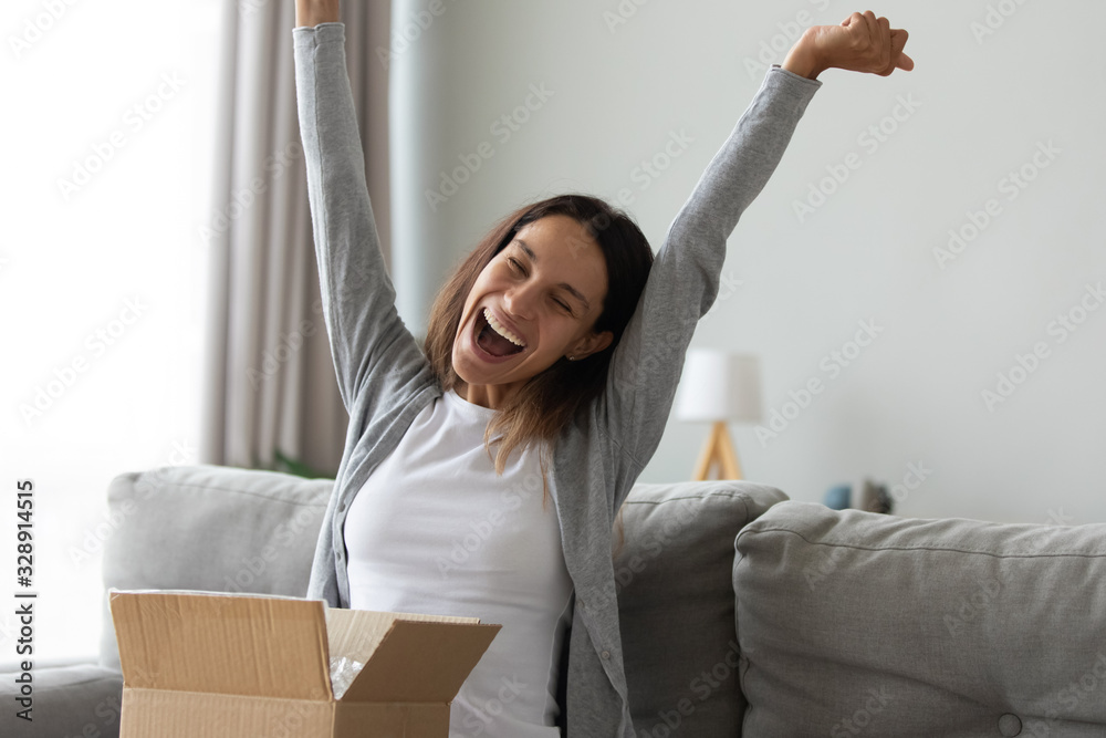 Overjoyed millennial Caucasian girl feel excited unpacking cardboard delivery box with Internet order shopping online, happy young woman triumph with good quality product buying things on web - obrazy, fototapety, plakaty 