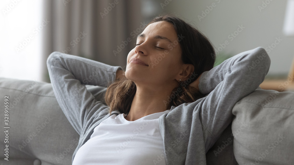 Happy millennial girl with eyes closed relax on comfortable couch in living room take nap daydream at home, smiling young Caucasian woman rest on cozy sofa breathing fresh air, stress free concept - obrazy, fototapety, plakaty 