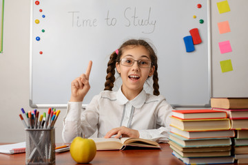 Smart school girl pointing index finger up. Concept of brilliant idea