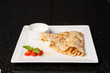 Pancake with ham, cheese and sour cream sauce. Food concept on a white plate and black background