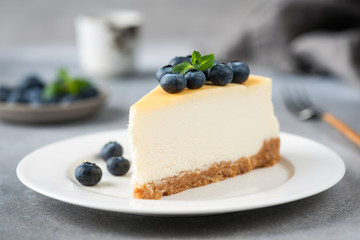 Wall Mural - Cheesecake slice with blueberries on white plate, closeup view. Tasty cream cake