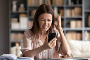 Head shot young woman irritated by bad cellphone work. Angry female client dissatisfied with application error, mobile system crash, bad internet connection. Unhappy lady annoyed by spam scam message.