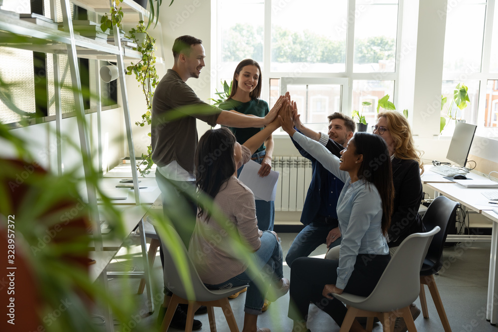 Excited multiracial colleagues give high five celebrate shared business ...