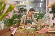 Portrait of female small business owner managing accounting books while using laptop at table in flower shop, copy space