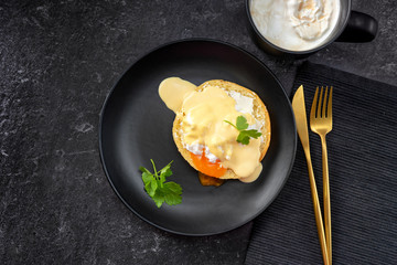 Wall Mural - Top view of poached egg in a black plate and gold cuttlery