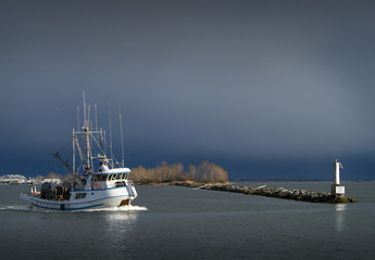 Wall Mural - Fishing Seiner Steveston Harbor. A seine boat travels out of the entrance of Steveston Harbor into Georgia Strait. Storm clouds loom in the background.