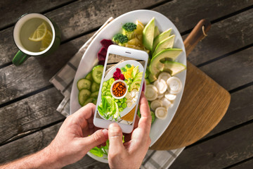 Canvas Print - Food photography on phone. Food blogging content concept. Male hands take photo of vegan plate with screen phone