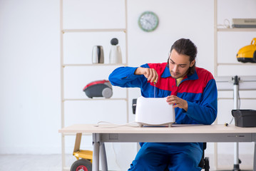 Young male contractor repairing toaster at workshop