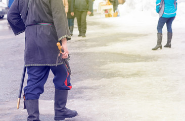 Cossack whip in the hand of a Cossack who goes in national costume, in kirzov boots and with a saber in winter on a crowded street