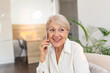 © Graphicroyalty - Happy senior woman using mobile phone at home. Smiling cool old woman with white hair sitting on sofa and messaging with smartphone. Beautiful stylish elderly lady talking on cellphone.