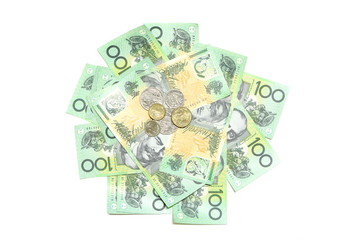 Many coins of Australian money on group of 100 dollar Australian notes pile background on white background