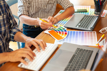 A team of graphic designers are designing their work on the office desks.